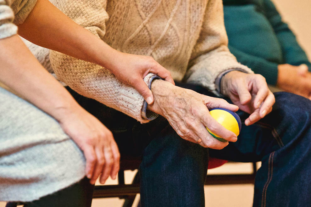 Carer holding arm of elderly patient waiting to throw a ball