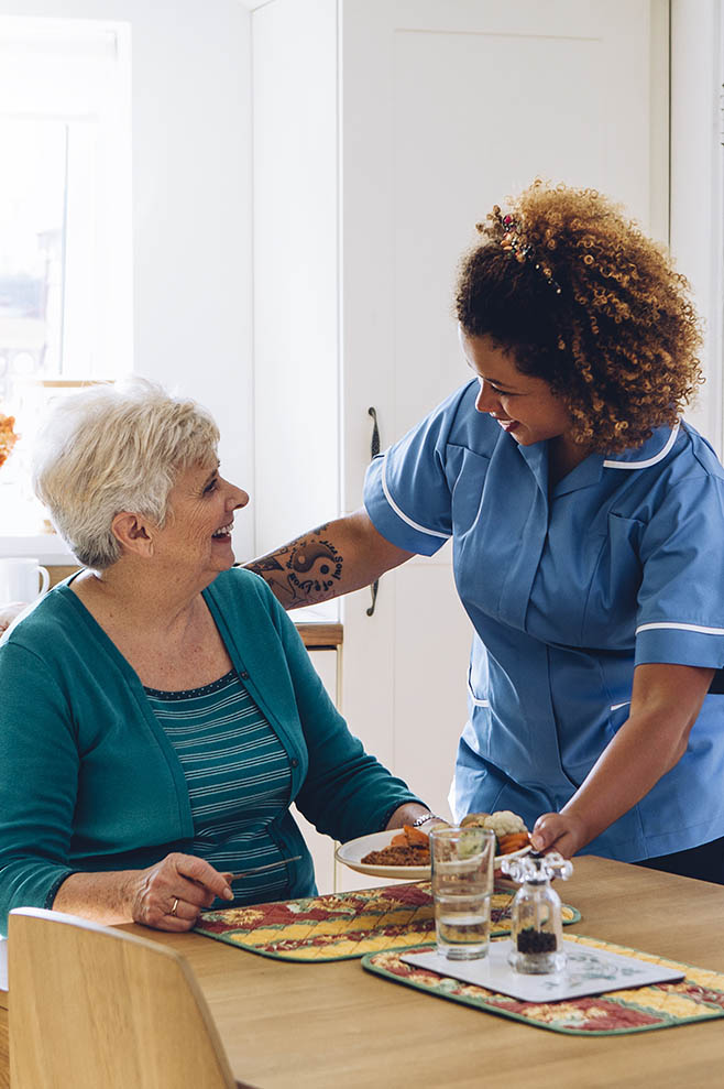 Home Care Assistant helping senior woman with meal