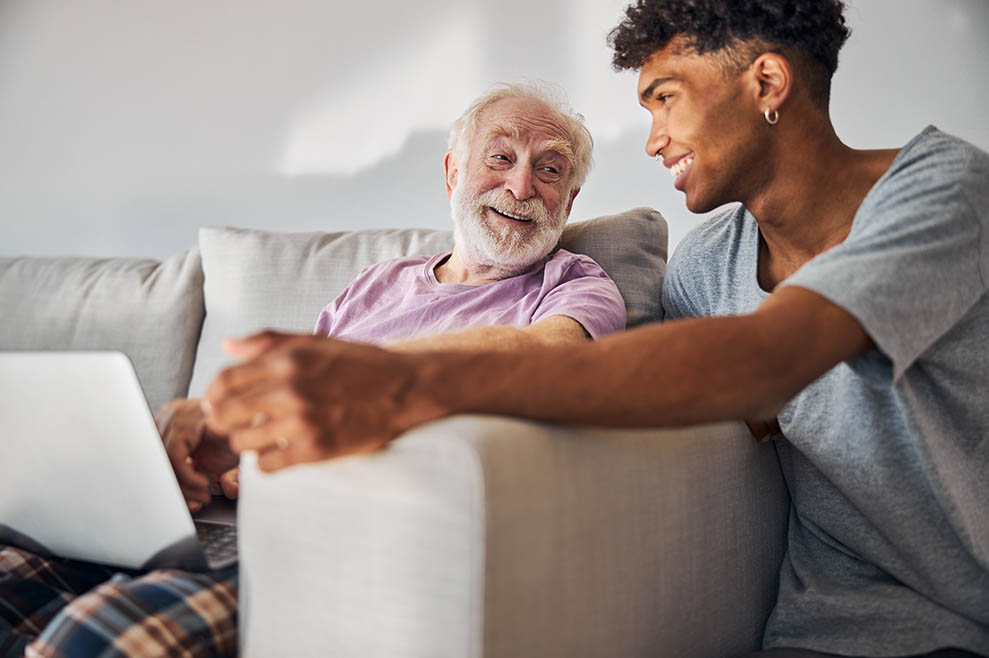 Young male carer assisting elderly man at home